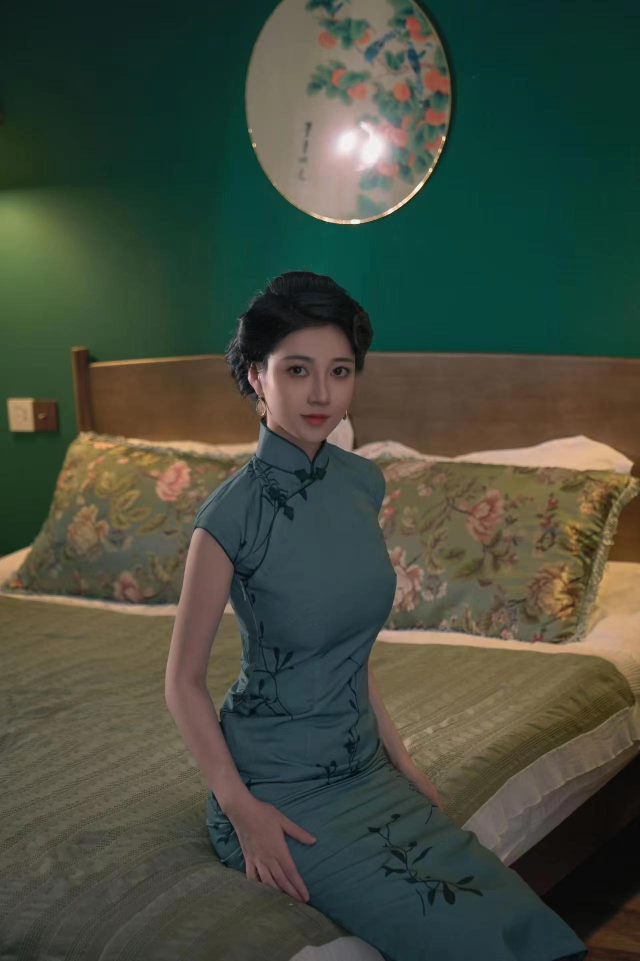 She sat on the edge of the bed like a celadon lady, her emerald cheongsam wrapped around her slender figure, only the pearl button on her collar rose and fell slightly with her breathing.